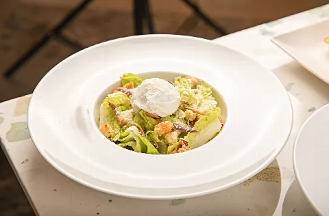 Caesar salad with a poached egg in a white bowl