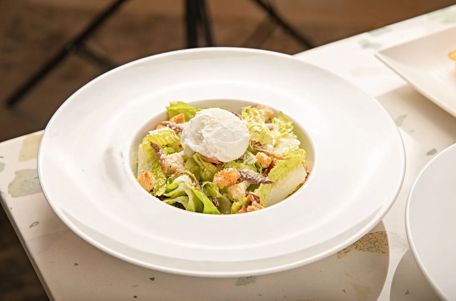 Caesar salad with a poached egg in a white bowl