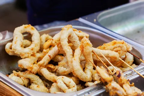 Golden fried calamari rings on a metal tray