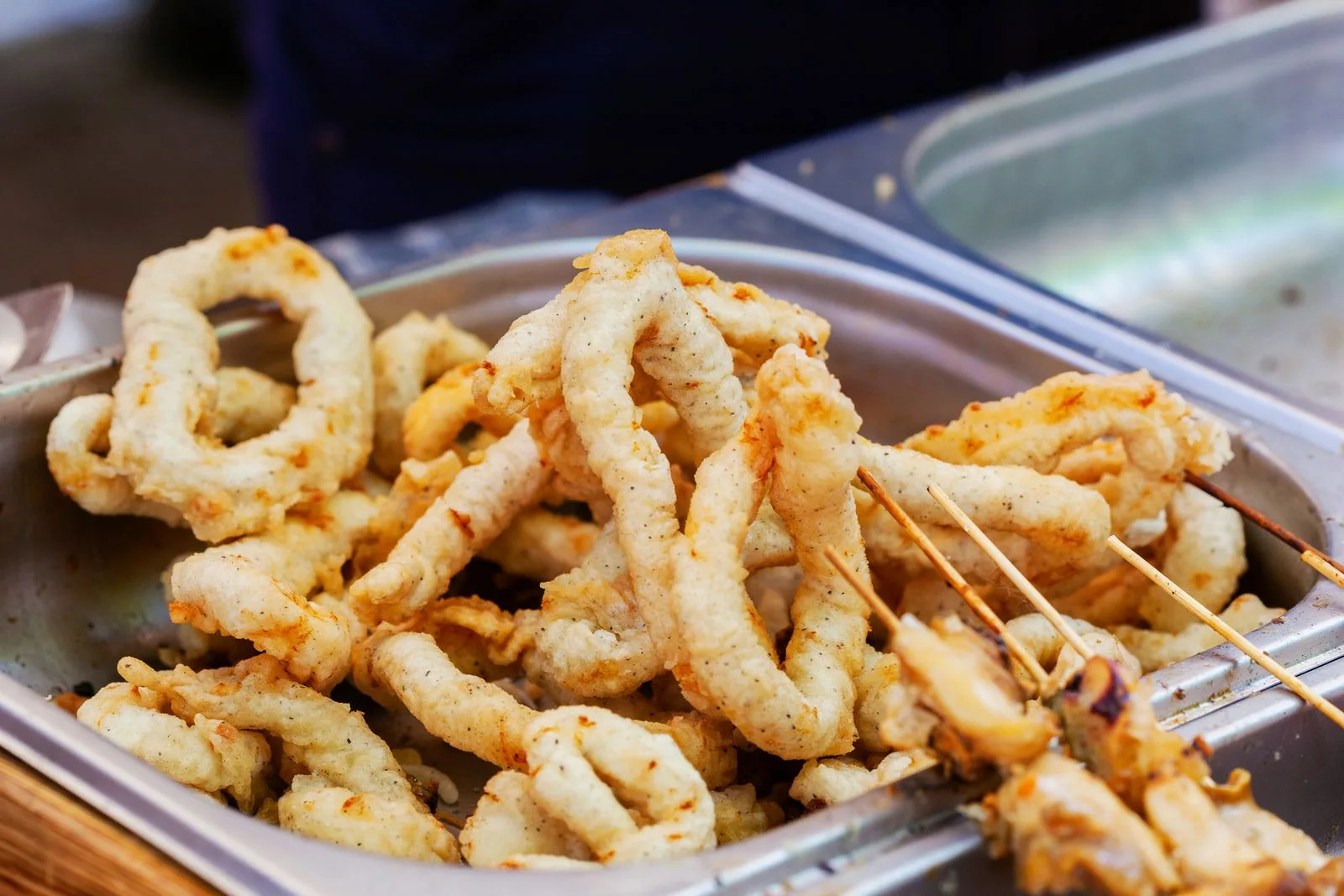 Golden fried calamari rings on a metal tray