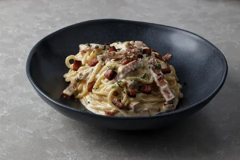 Spaghetti carbonara with pancetta in a dark bowl